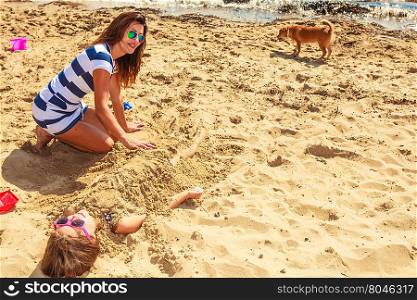 Mother and daughter playing on beach.. Play and fun in summer. Adorable girl daughter having fun with her mommy. Family spending time together on beach seaside.