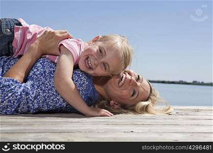 Mother and daughter playing on dock