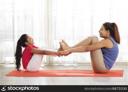 Mother and daughter playing on exercise mat