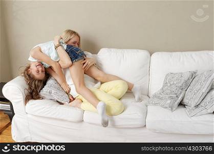 Mother and daughter playing on sofa
