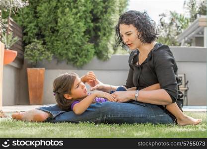 Mother and daughter playing outside in the back garden on a nice summer day, spending quality time with each other.