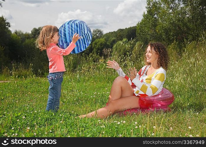mother and daughter playing with ball in summer day at wood