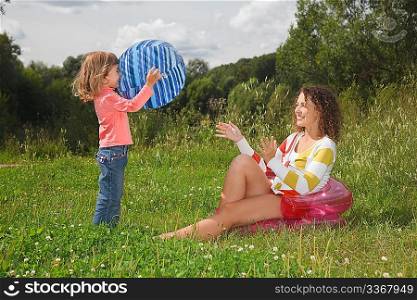 mother and daughter playing with ball in summer day at wood