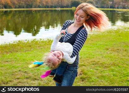 Mother and daughter playing with color feathers in a park lake