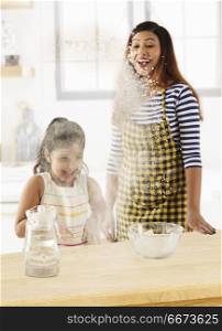 Mother and daughter playing with flour in kitchen