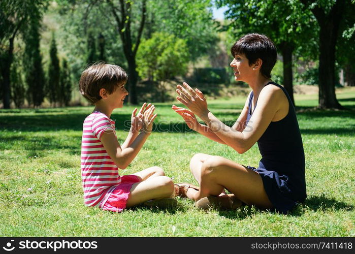 Mother and daughter playing with hands in city park. Happy loving family.. Mother and daughter playing with hands in city park