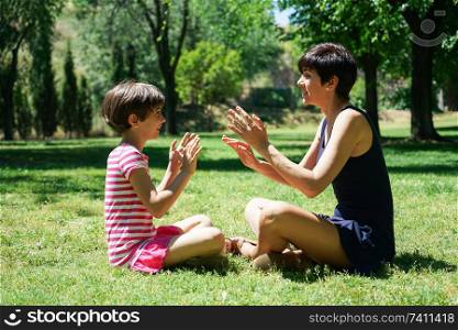 Mother and daughter playing with hands in city park. Happy loving family.. Mother and daughter playing with hands in city park