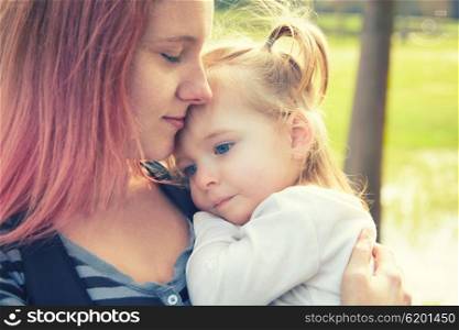 Mother and daughter portrait hug kissing in a park outdoor