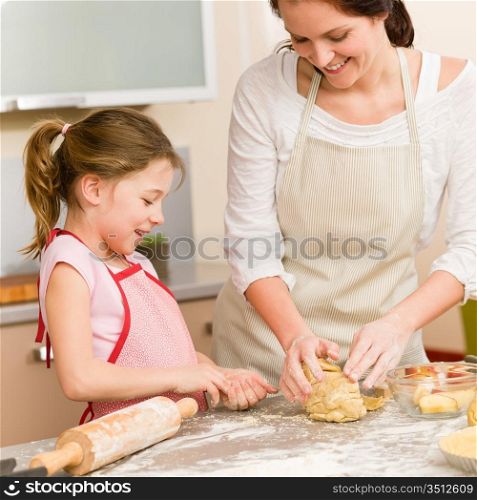 Mother and daughter prepare dough baking apple cake happy together