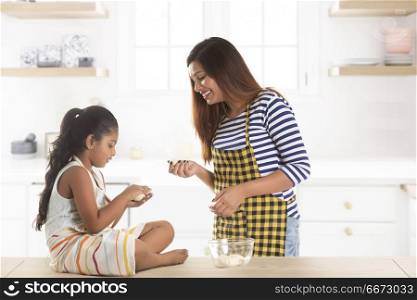 Mother and daughter preparing dough balls in kitchen
