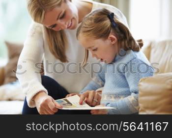 Mother And Daughter Reading Story At Home Together