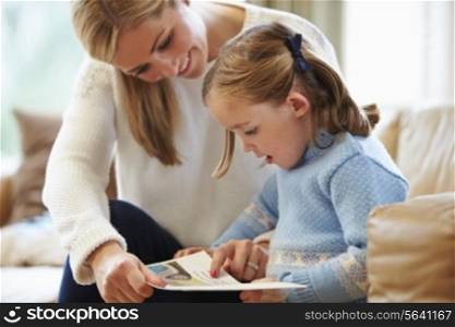 Mother And Daughter Reading Story At Home Together