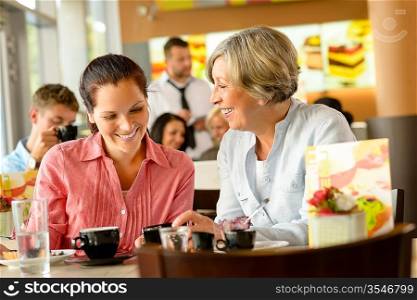 Mother and daughter relaxing in a cafe women restaurant happy