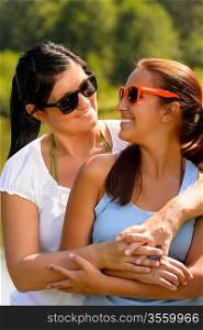 Mother and daughter relaxing in park smiling teen summer affectionate