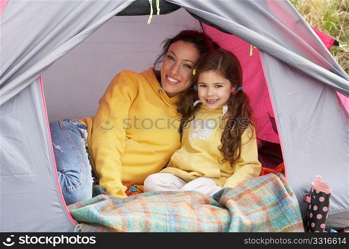 Mother And Daughter Relaxing Inside Tent On Camping Holiday