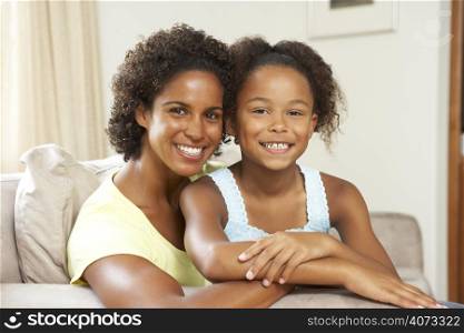 Mother And Daughter Relaxing On Sofa At Home