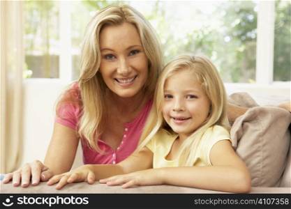 Mother And Daughter Relaxing On Sofa At Home