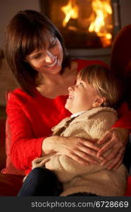 Mother And Daughter Relaxing On Sofa By Cosy Log Fire