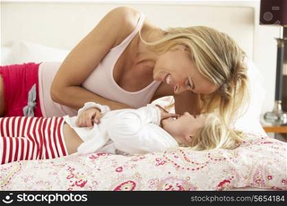 Mother And Daughter Relaxing Together In Bed