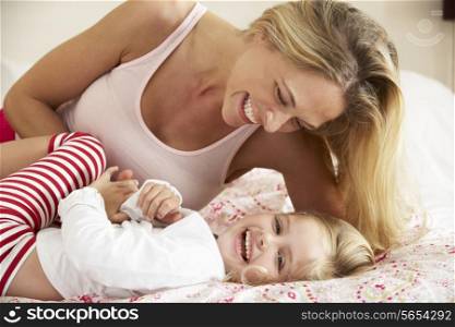 Mother And Daughter Relaxing Together In Bed
