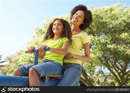 Mother And Daughter Riding On Seesaw In Park