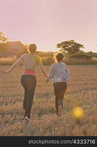 Mother and daughter running in field