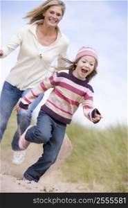 Mother and daughter running on beach smiling