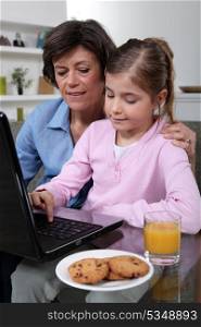 Mother and daughter sat at laptop