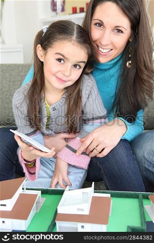 Mother and daughter sat by scale model of housing