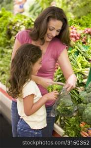 Mother and daughter shopping for broccoli at a grocery store