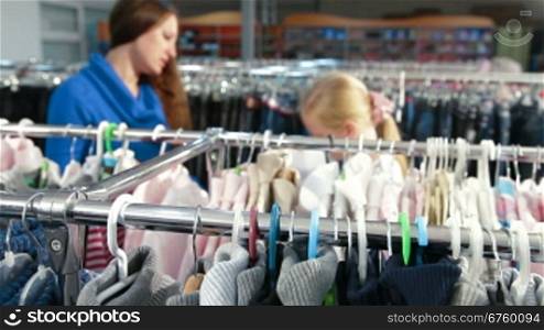 Mother and daughter shopping for girls clothes in a clothing store, focus on the foreground