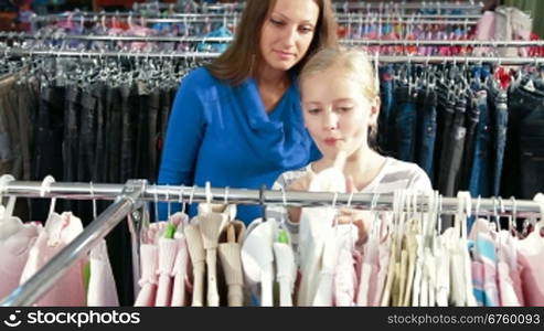 Mother and daughter shopping for girls clothes in a clothing store, looking sweater