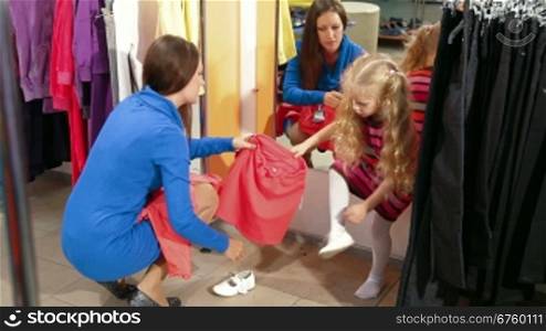 Mother and daughter shopping for girls clothes in a clothing store, trying on top & skirt set