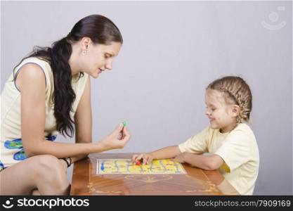 Mother and daughter sitting at a table and play a Board game