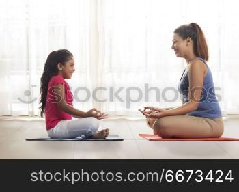 Mother and daughter sitting face to face doing meditation