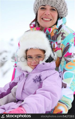 Mother and daughter sitting in the snow