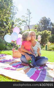 Mother and daughter sitting on blanket in garden with pinwheel