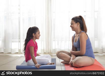 Mother and daughter sitting on exercise mat