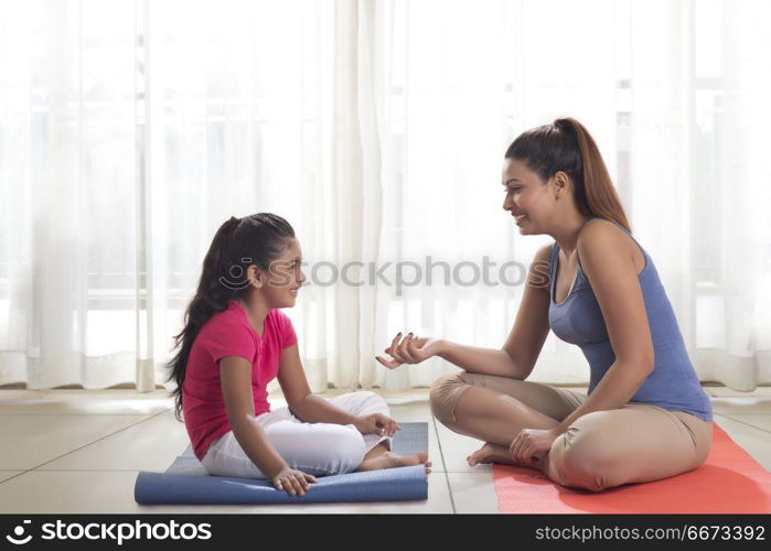 Mother and daughter sitting on exercise mat