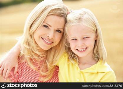 Mother And Daughter Sitting On Straw Bales In Harvested Field