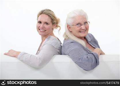 Mother and daughter sitting on white sofa