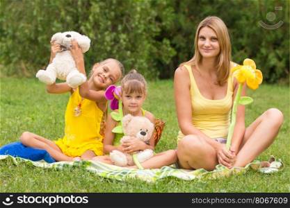 Mother and daughter sitting with soft toys on a picnic