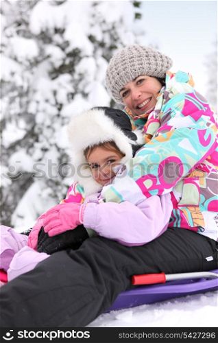 Mother and daughter sledging together