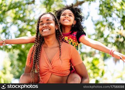 Mother and daughter smiling and enjoying a day together at the park.