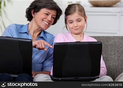 Mother and daughter son on sofa with their own laptops