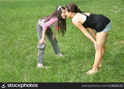 mother and daughter stand on the grass