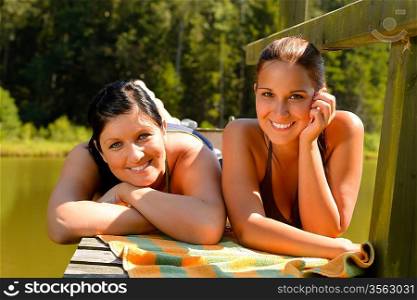 Mother and daughter sunbathing on pier smiling teen relaxing vacation