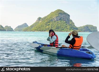 Mother and daughter take pictures on kayak. Two women are mother and daughter using a camera take pictures on kayak while travel by boat with happy on the sea during summer at Ko Wua Ta lap islands in Mu Ko Ang Thong National Park, Surat Thani, Thailand