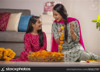 Mother and daughter together enjoying while composing flower garland