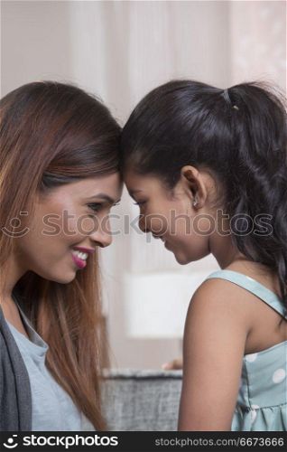 Mother and daughter touching foreheads
